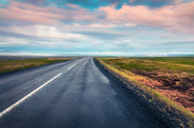 Renkli bulutlu gökyüzü ile boş asfalt yol. İzlanda, Avrupa 'da güzel bir açık hava manzarası. Seyahat kavramı arkaplanı resmi