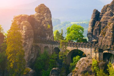 Bastei Köprüsü 'ndeki İsviçre Ulusal Parkı' nda kumtaşı uçurumunda puslu bir sabah. Almanya, Saksonya, Avrupa 'da renkli bahar gündoğumu. İşlenmiş fotoğraf sonrası sanatsal stil.