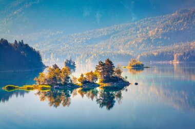 Eibsee gölünde güneş ışığıyla parlayan renkli bir ada. Alman Alpleri, Bavyera, Garmisch-Partenkirchen köyü, Almanya, Avrupa 'da muhteşem bir açık hava sahnesi. İşlenmiş fotoğraf sonrası sanatsal stil.
