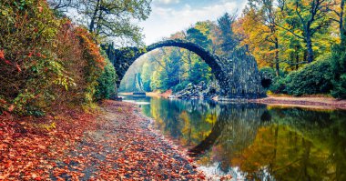 Azalea ve Rhododendron Park Kromlau 'nun panoramik sabah sahnesi, Almanya, Avrupa. Rakotz Köprüsü 'nün (Rakotzbrucke, Şeytanın Köprüsü) çekici sonbahar manzarası. Seyahat konsepti arka planı.