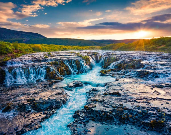 View from flying drone. Exciting summer sunrise on Bruarfoss Waterfall, secluded spot with cascading blue waters. Impressive morning scene of Iceland, Europe. Beauty of nature concept background.