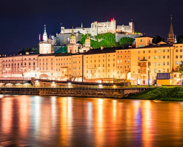 Old town of Salzburg reflected in the calm waters of Salzach river. Incredible night cityscape of Salzburg with Hohensalzburg Castle on background. Austria, Europe. Traveling concept background.