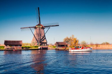 Hollanda 'daki Kinderdijk Müzesi' nin ünlü yel değirmenleri. Kırsal kesimde güneşli bir bahar sabahı. Hollanda, Avrupa 'da renkli bir açık hava sahnesi. UNESCO Dünya Mirası Alanı. İşlenmiş fotoğraf sonrası sanatsal stil.