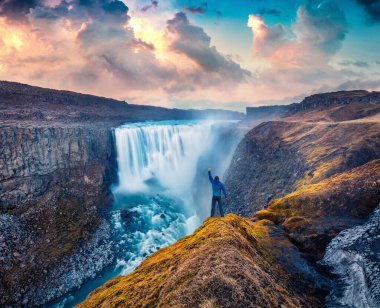 Avrupa 'nın en güçlü şelalesinin düşen sularının kıyısında duran turist Dettifoss. Jokulsargljufur Ulusal Parkı, İzlanda 'da etkileyici bir yaz günü..