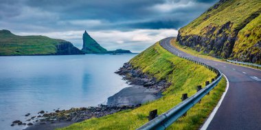 Arka planda Faroe Adaları ve Tindholmur uçurumlarının dramatik yaz manzarası. Vagar Adası, Danimarka, Avrupa 'nın panoramik sabah manzarası. Seyahat konsepti arka planı.
