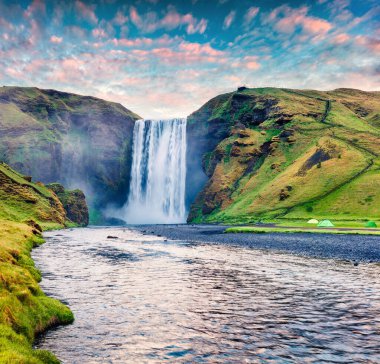 Skoga Nehri 'ndeki devasa Skogafoss Şelalesi' nde muhteşem bir yaz gündoğumu. Güney İzlanda, Avrupa 'da renkli bir yaz manzarası. İşlenmiş fotoğraf sonrası sanatsal stil.