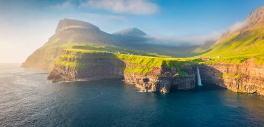 Uçan İHA 'nın görüntüsü. Mulafossur Şelalesi 'nin panoramik sabah sahnesi. Vagar Adası 'nın güneşli yaz manzarası, Faroe Adaları, Danimarka, Avrupa. Doğa konseptinin güzelliği.