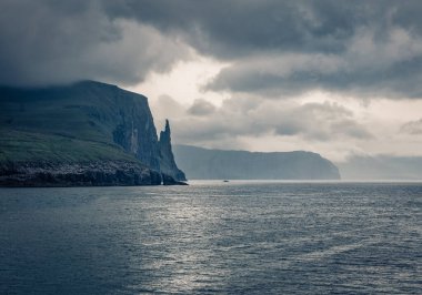 Vagar adasında Trollkonfingur kayalıkları olan muhteşem Faroe manzarası. Sandavagur köyü, Faroe Adaları, Danimarka Krallığı, Avrupa 'nın kenar mahallelerinin dramatik yaz manzarası. 