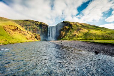 Skoga nehrindeki Skogafoss Şelalesi 'nin harika yaz manzarası. İzlanda, Avrupa 'da renkli bir yaz sahnesi. İşlenmiş fotoğraf sonrası sanatsal stil.