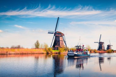 Hollanda 'daki Kinderdijk Müzesi' nin ünlü yel değirmenleri. Kırsal kesimde güneşli bir bahar sabahı. Hollanda, Avrupa 'da renkli bir açık hava sahnesi. UNESCO Dünya Mirası Alanı. İşlenmiş fotoğraf sonrası sanatsal stil.