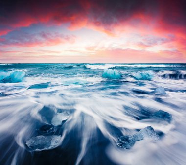 Jokulsarlon sahilindeki dalgalarla yıkanmış buz blokları. Vatnajokull Ulusal Parkı, İzlanda, Avrupa 'da dramatik bir yaz gündoğumu. Doğa konseptinin güzelliği.