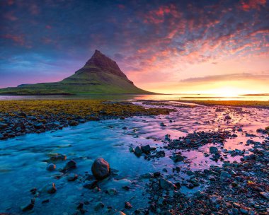 Kirkjufell dağıyla birlikte renkli bir yaz günbatımı. Snaefellsnes yarımadasında dramatik bir sahne. Atlantik Okyanusu, İzlanda, Avrupa 'da gelgit ile birlikte..