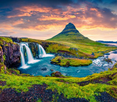 Ünlü Kirkjufellsfoss Şelalesi ve Kirkjufell Dağı 'nda yaz günbatımı. Snaefellsnes yarımadasında dramatik bir akşam sahnesi, İzlanda, Avrupa. İşlenmiş fotoğraf sonrası sanatsal stil.