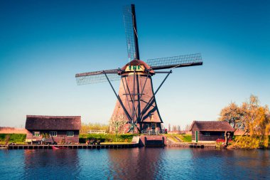 Hollanda 'daki Kinderdijk Müzesi' ndeki ünlü zihin değirmenleri. Kırsal kesimde güneşli bir bahar sabahı. Hollanda, Avrupa 'da renkli bir açık hava sahnesi. UNESCO Dünya Mirası Alanı. İşlenmiş fotoğraf sonrası sanatsal stil