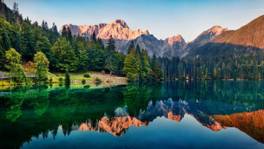 Fusine Gölü 'nün sakin sabah manzarası. Julian Alps 'te renkli bir yaz gündoğumu. Arka planda Mangart zirvesi, Udine ili, İtalya, Avrupa. Doğa konseptinin güzelliği