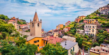 Tepe şehirleri Cique Terre 'nin ilk şehri San Giovanni Battista Kilisesi' nin kulesine sahip Riomaggiore. Liguria, İtalya, Avrupa 'nın muhteşem yaz sahnesi. Seyahat konsepti arka planı.