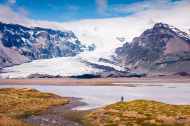 Vatnajokull buzulundan eriyen buz. Vatnajokull Ulusal Parkı 'nda, İzlanda, Avrupa' da gölün kıyısında bir adamla renkli bir yaz sahnesi. İşlenmiş fotoğraf sonrası sanatsal stil.