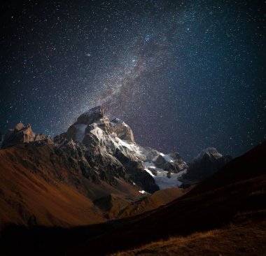 Karanlık yıldızlı gökyüzü ile Ushba Dağı 'nın gece manzarası. Kafkasya dağlarında güzel bir açık hava manzarası, Yukarı Svaneti, Avrupa. 