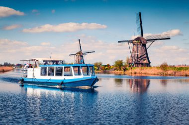 Hollanda 'daki Kinderdijk Müzesi' nin ünlü yel değirmenleri. Kırsal kesimde güneşli bir bahar sabahı. Hollanda, Avrupa 'da renkli bir açık hava sahnesi. UNESCO Dünya Mirası Alanı. İşlenmiş fotoğraf sonrası sanatsal stil.