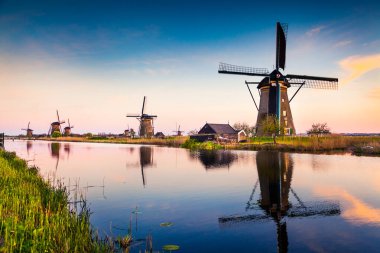 Hollanda 'daki Kinderdijk Müzesi' ndeki ünlü yel değirmenleri, UNESCO Dünya Mirası Bölgesi. Kırsalda renkli bir bahar günbatımı. Hollanda, Avrupa 'da muhteşem bir açık hava sahnesi. İşlenmiş fotoğraf sonrası sanatsal stil.