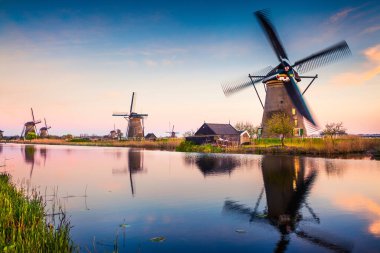 Hollanda 'daki Kinderdijk Müzesi' ndeki ünlü zihin değirmenleri, UNESCO Dünya Mirası Alanı. Kırsalda renkli bir bahar günbatımı. Hollanda, Avrupa 'da muhteşem bir açık hava sahnesi. İşlenmiş fotoğraf sonrası sanatsal stil.