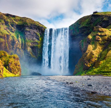 Skoga Nehri 'ndeki devasa Skogafoss Şelalesi' nin muhteşem yaz manzarası. Güney İzlanda, Avrupa 'da renkli bir yaz manzarası. İşlenmiş fotoğraf sonrası sanatsal stil.