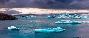 Jokulsarlon 'un buzul gölünde mavi buzdağları yüzüyor. Vatnajokull Ulusal Parkı, Güneydoğu İzlanda, Avrupa 'da renkli günbatımı manzarası. İşlenmiş fotoğraf sonrası sanatsal stil.
