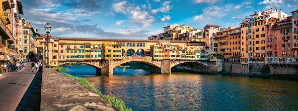 Panoramic view of medieval arched river bridge with Roman origins - Ponte Vecchio over Arno river. Colorful summer cityscape of Florence, Italy, Europe. Traveling concept background.