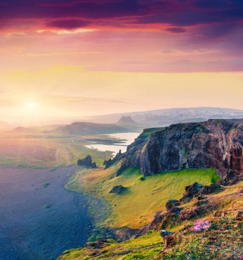 Dyrholaey yarımadasının renkli akşam manzarası. Güney İzlanda 'da etkileyici bir yaz günbatımı, Vic Köyü, Avrupa. Doğa konseptinin güzelliği