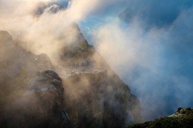 Birçok turist uçurumun kenarında, Norveç 'in popüler eğlencesi Preikestolen. Norveç 'in güneybatısındaki Ryfylke bölgesinde bulunan Lysefjorden fiyordunun sisli yaz sabahı manzarası. 