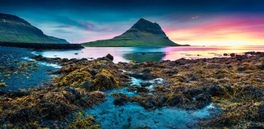 Kirkjufell dağıyla birlikte renkli bir yaz günbatımı. Snaefellsnes yarımadasında dramatik bir sahne. Atlantik Okyanusu, İzlanda, Avrupa 'da gelgit ile birlikte.. 