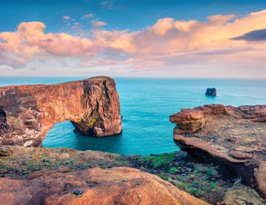 Dyrholaey kemerinin resimli akşam sahnesi. İzlanda 'nın güney kıyısındaki Dyrholaey Doğa Koruma Alanı' nda renkli bir yaz günbatımı. İşlenmiş fotoğraf sonrası sanatsal stil.