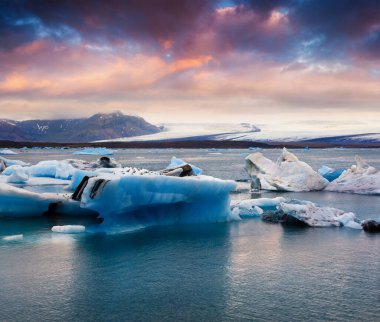 Jokulsarlon 'un buzul gölünde mavi buzdağları yüzüyor. Vatnajokull Ulusal Parkı, Güneydoğu İzlanda, Avrupa 'da renkli bir gün batımı. İşlenmiş fotoğraf sonrası sanatsal stil.