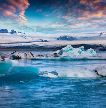 Jokulsarlon 'un buzul gölünde mavi buzdağları yüzüyor. Vatnajokull Ulusal Parkı, Güneydoğu İzlanda, Avrupa 'da renkli bir gün batımı. İşlenmiş fotoğraf sonrası sanatsal stil.