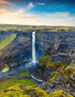 Turist cep telefonuyla İzlanda 'nın en yüksek ikinci şelalesinin fotoğrafını çekiyor. Haifoss. Derin Kanyon 'un resimli gündoğumu manzarası. İzlanda 'ya git. Doğa konseptinin güzelliği.