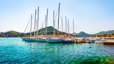 Nydri Limanı 'nın güneşli yaz dulu. İyon Denizi 'nin renkli sabah deniz manzarası. Lefkada Adası, Yunanistan, Avrupa 'nın güneşli açık hava manzarası. Seyahat konsepti arka planı.