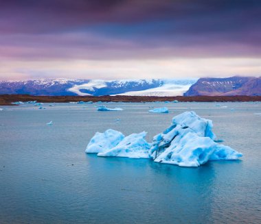Jokulsarlon 'un buzul gölünde yüzen mavi buzdağları. Vatnajokull Ulusal Parkı, Güneydoğu İzlanda, Avrupa 'da renkli yaz günbatımı. İşlenmiş fotoğraf sonrası sanatsal stil.