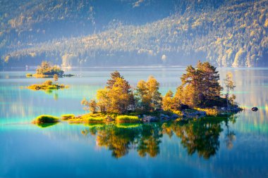Eibsee gölünde güneş ışığıyla parlayan renkli bir ada. Alman Alpleri, Bavyera, Garmisch-Partenkirchen köyü, Almanya, Avrupa 'da muhteşem bir açık hava sahnesi. İşlenmiş fotoğraf sonrası sanatsal stil.