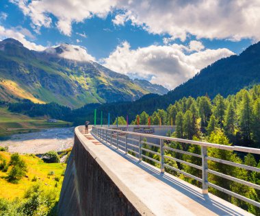 Fotoğrafçı, Orlegna nehrindeki barajda fotoğraf çekiyor. Maloja geçidinin tepesinden güneşli yaz manzarası. İsviçre Alpleri, Grisons, İsviçre, Avrupa kantonunda Upper Engadine. İşlenmiş fotoğraf sonrası sanatsal stil.