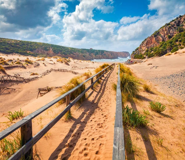 Cala Domestica plajının güneşli sabah manzarası. Sardunya, İtalya, Avrupa 'nın parlak yaz manzarası. Canyon di Cala Domestica 'daki yaya köprüsü. Seyahat konsepti arka planı.
