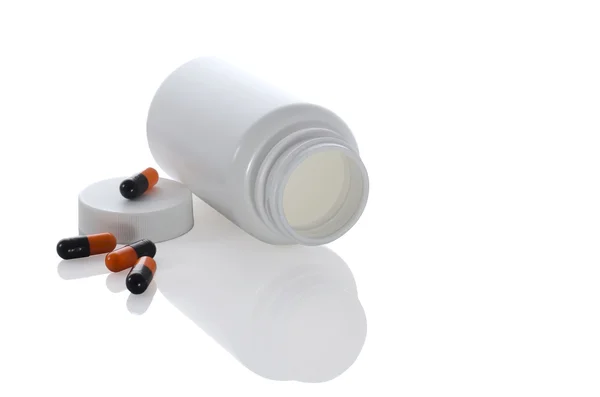 Few pills of a black and orange colors with white jar and bottle — Stock Photo, Image
