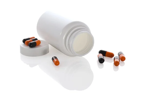 Few pills of a black and orange colors with white jar and bottle — Stock Photo, Image