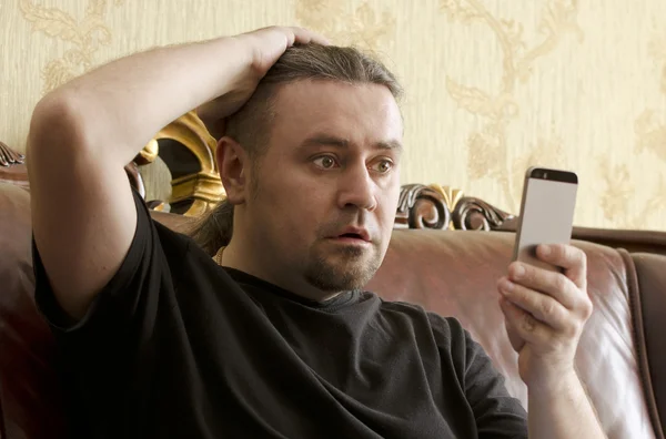 Zaskoczony mężczyzna patrząc na telefon komórkowy — Zdjęcie stockowe