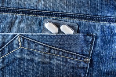 Kot pantolonun cebinde haplar. Arka cebinde beyaz haplar var. Sağlık konsepti