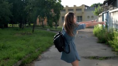 Genç bir kadın sokakta yürüyor, zıplıyor ve eğleniyor. Bayan model tatilde eğleniyor. Yavaş çekim