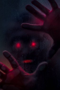 Islak duş camına kanlı eli olan bir adamın korku sahnesi. Tonlanmış görüntü. Korku konsepti. Dikey resim