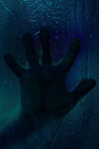 Bloody hand against wet shower glass. Horror concept. Toned image. Vertical image
