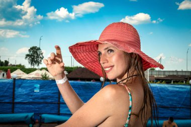 Mayolu ve plaj şapkalı genç bir kadının portresi. Çekici esmer kadın gülümsüyor ve güneşleniyor