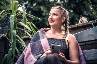 Açık kafede akıllı telefon kullanan genç bir kadın.