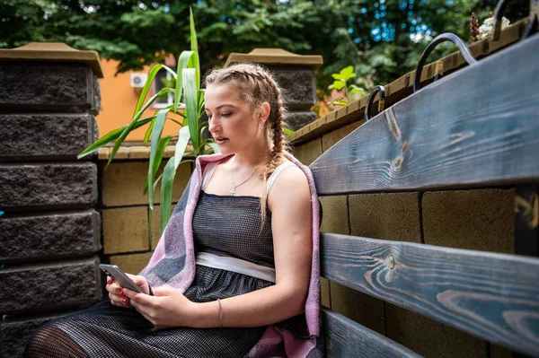 Açık kafede akıllı telefon kullanan genç bir kadın.